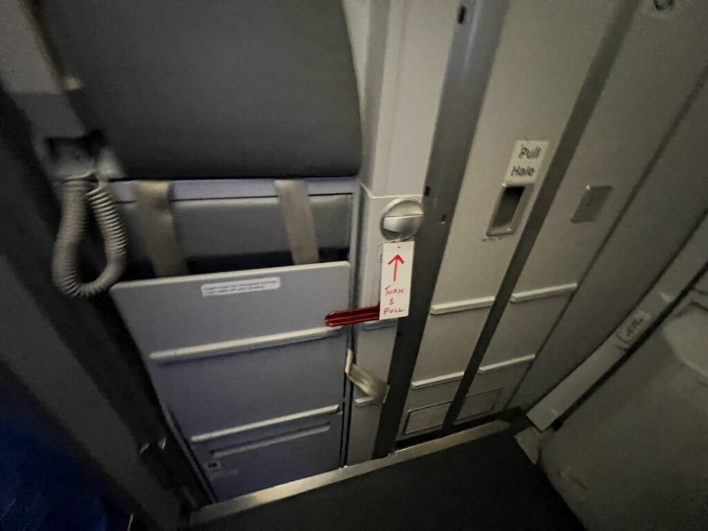 The lavatory door carries a flight crew jump seat, shown here. A sign points to the lav door handle.