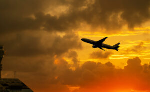 Airplane takeoff from airport with cloudy sky during sunrise