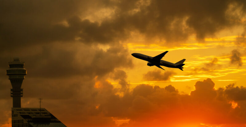 Airplane takeoff from airport with cloudy sky during sunrise
