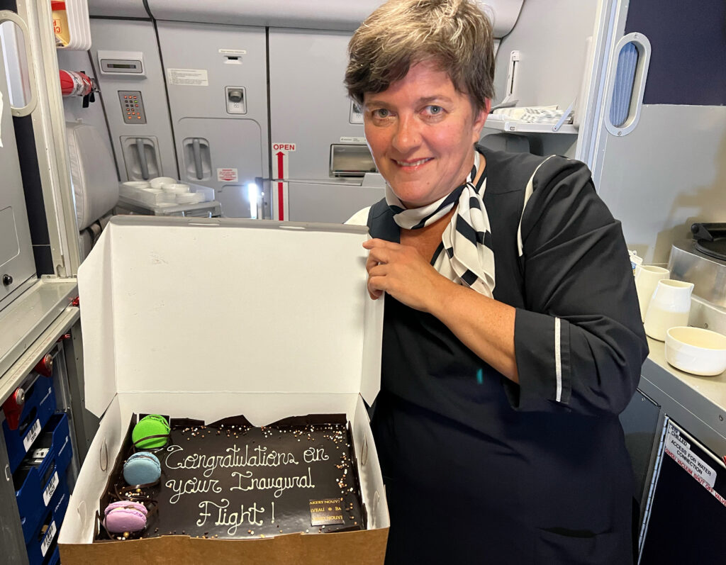 A Finnair cabin crew member is holding a a box open to show a celebratory chocolate cake. 