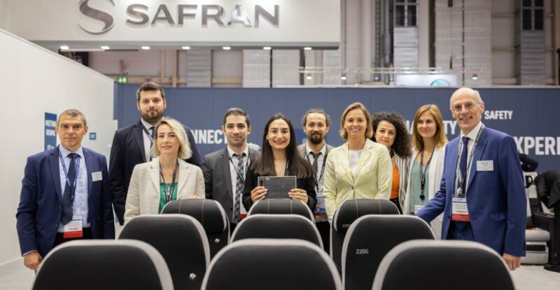 A group of Safran and SunExpress members stand behind the Z200 seat display at AIX 2022