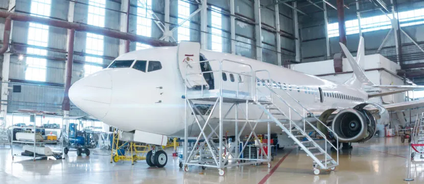 White passenger airplane in the MRO hangar. Airliner under maintenance.