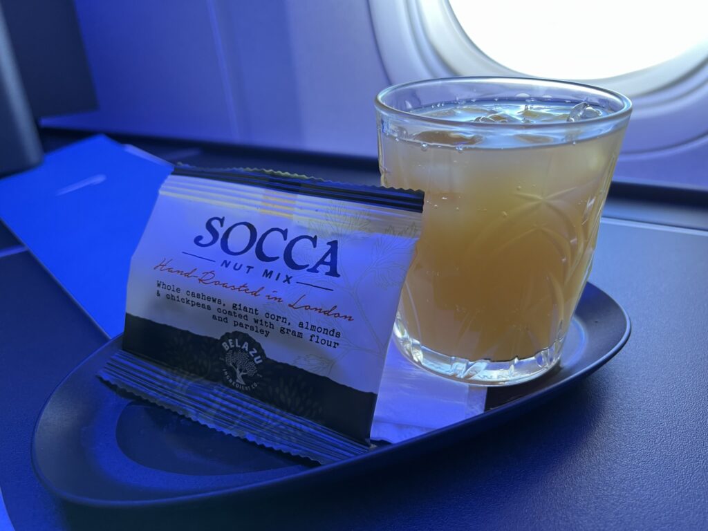 A drink and a snack are displayed on an elegant dish, and placed on the Club Suite's side table