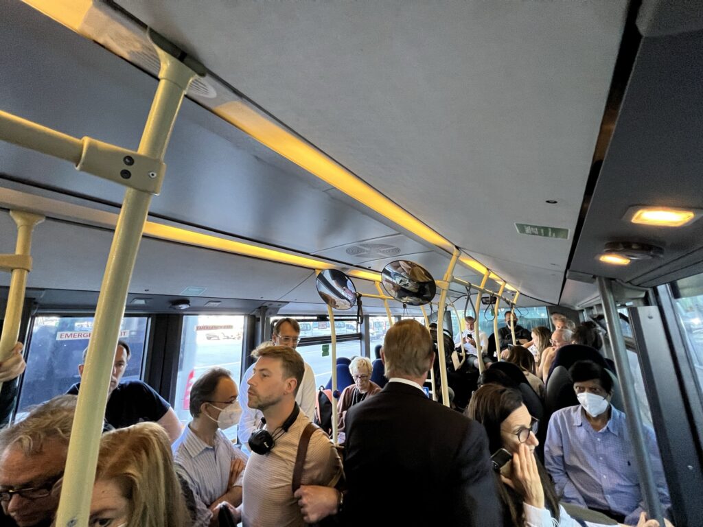 A crowded airport bus of passengers.