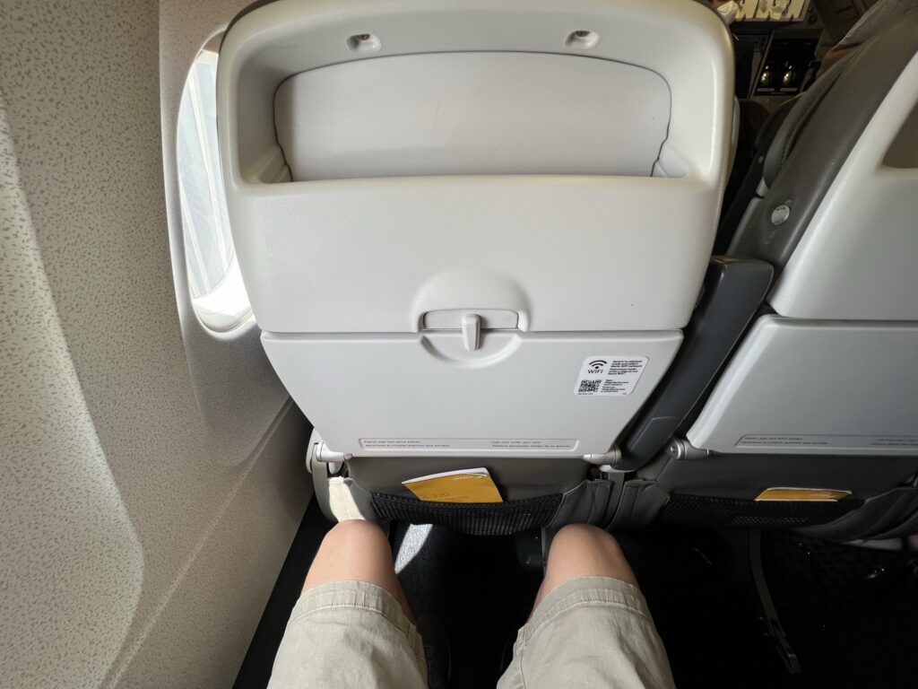 A man's knees are shown in the economy class seat of the Iberia A320