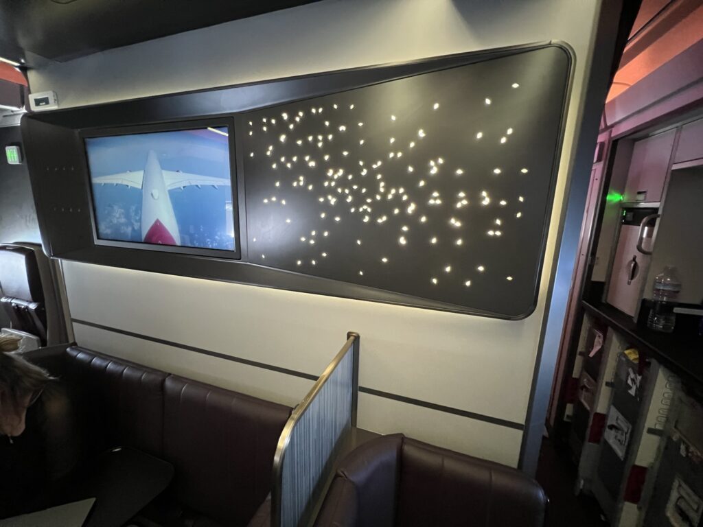 The Loft in Upper Class onboard the Virgin Atlantic A350-1000, featuring a large screen piping the tail cam content to viewers