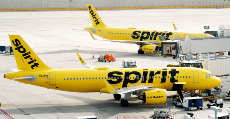 Spirit Airlines are parked at the gates of an airport. The bright yellow livery stands out with the big black Spirit lettering on the side.