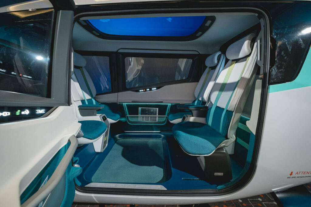 Eve cabin mockup that is being displayed at Embraer booth. The cabin is sleek and futuristic with slim seats in white and teal.