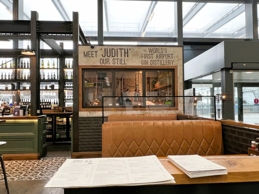 Two leather clad booths inside the restaurant, and a sign touting that the space includes the "world's first airport gin distillery"