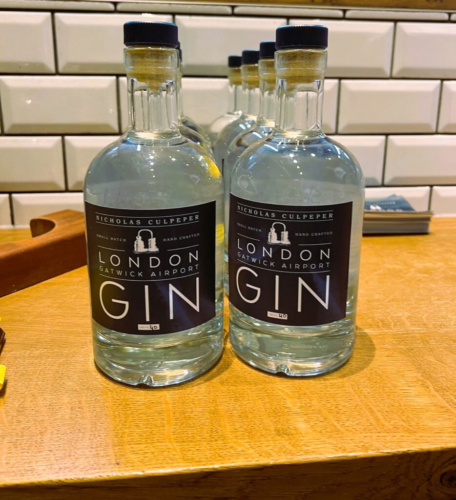 Minature bottles of gin lined up in two rows on a wooden table.