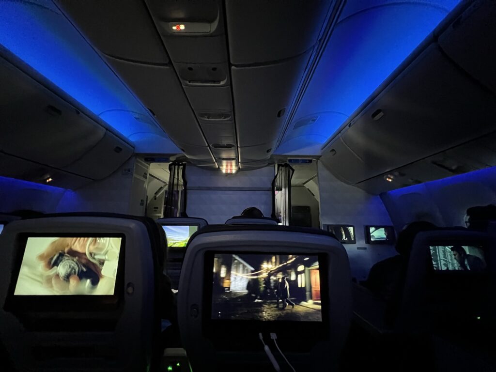 The Delta Premium Select cabin at night, with IFE screens flickering and blue LED lights adding to the mood