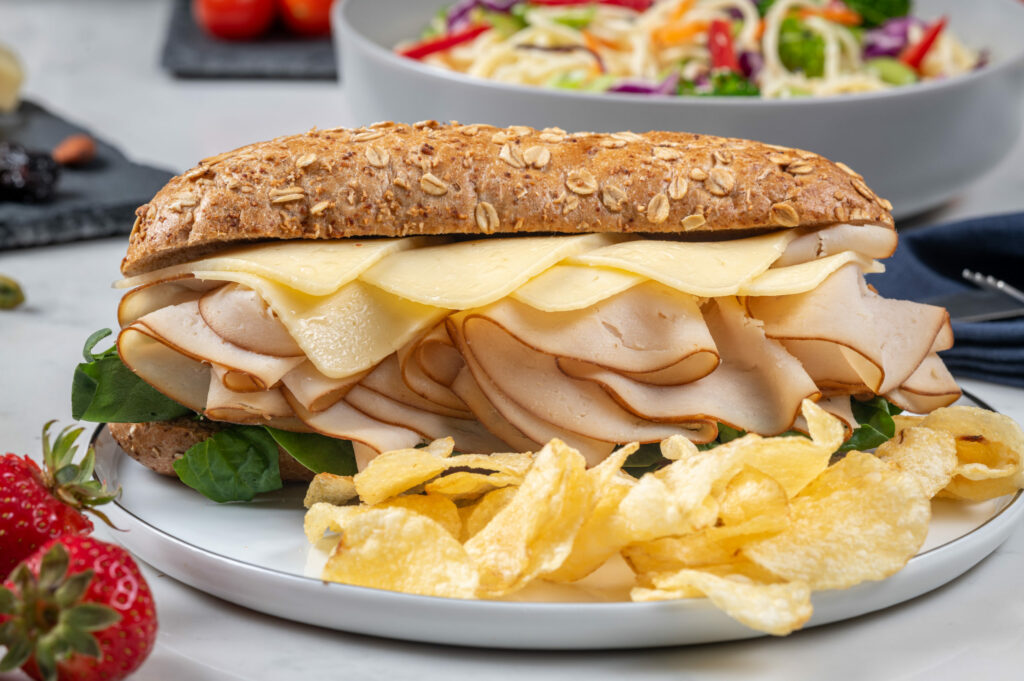 A large cheese and turkey sandwich with chips, available on Amtrak