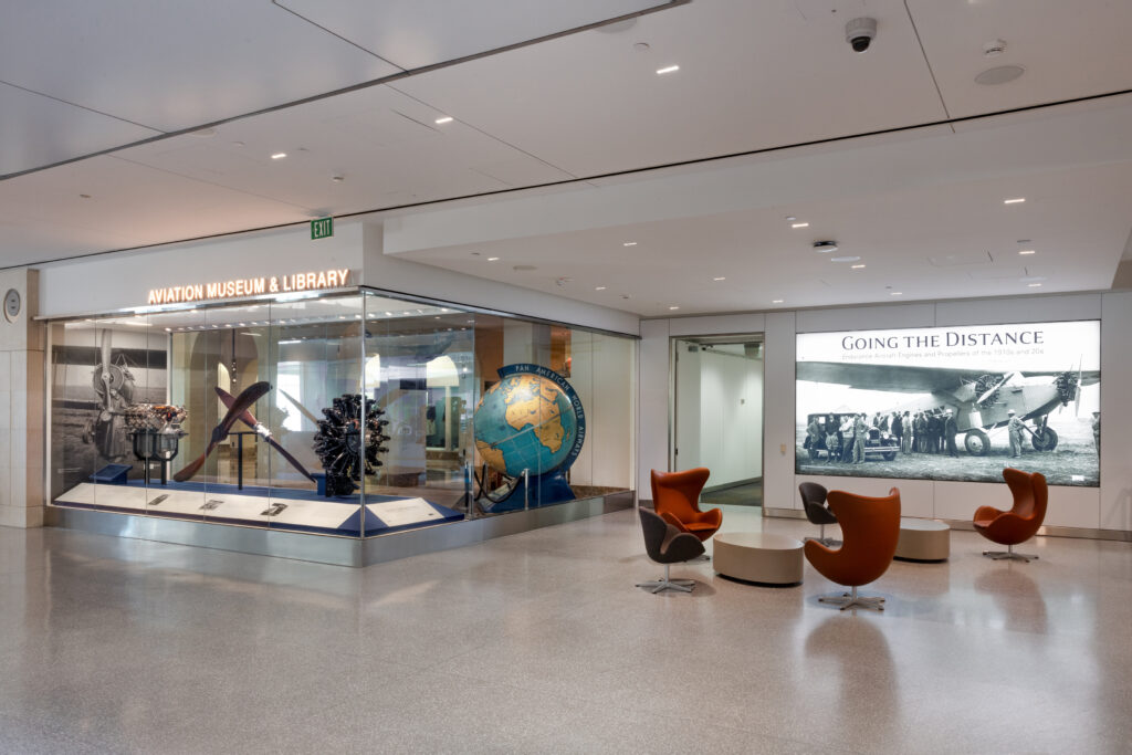 SFO Aviation Museum and Library has a selection of seats for passengers and displays a large globe and other artifacts in a glass viewing case.