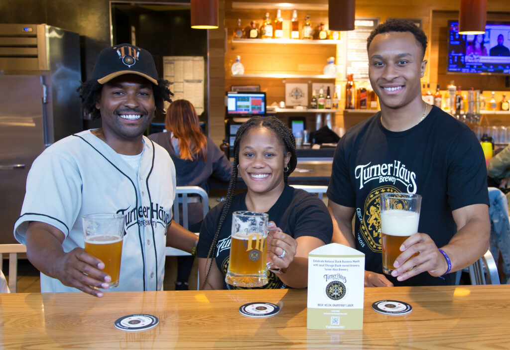 Two men and a womanare holding up a beer at the airport bar