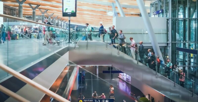 A group of people are going up an escalator in an airport.