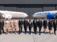 Both United and Emirates crew members walk side by side as an aircraft from each airline sits behind them facing each other.