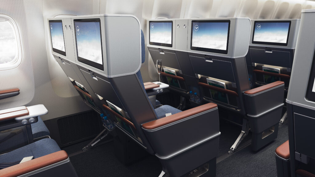 ZimPrivacy Premium Economy class seat on a Lufthansa aircraft. The seat is navy blue with dark wood-like accents and armrests. Part of the new Lufthansa new Allegris brand line