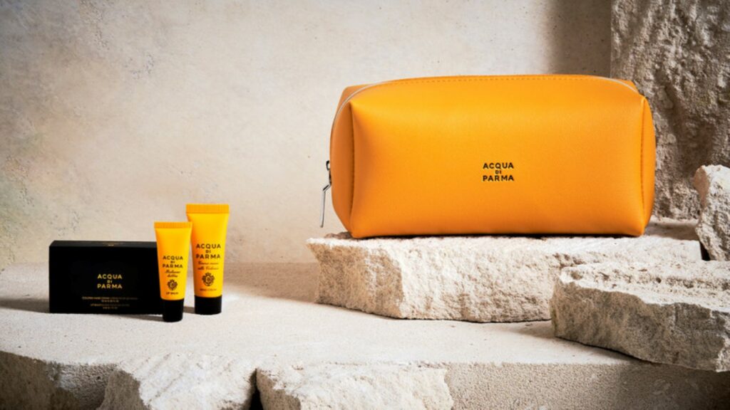 An orange Air Canada amenity kit is displayed next to two small orange hand cream bottles.