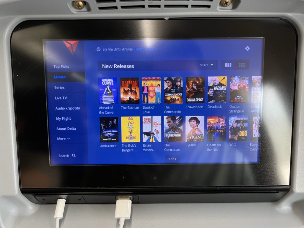 Panasonic IFE in the seatback of a Delta aircraft. Device cords are plugged in for charging.