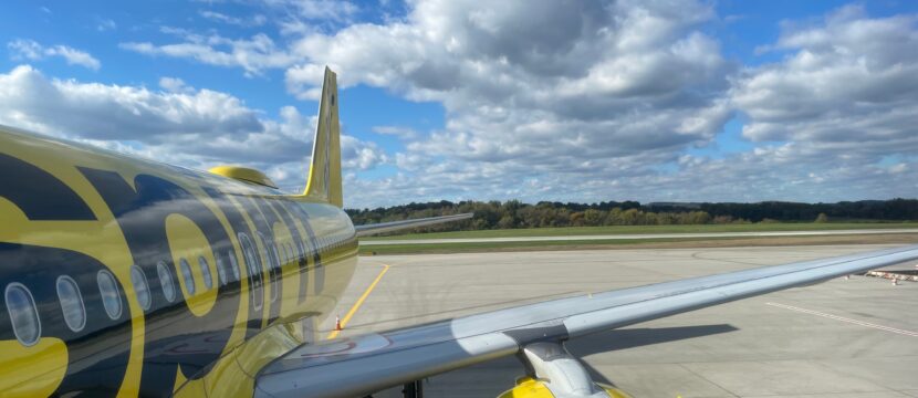 Spirit Airlines A320 parked at the gate on a sunny day.