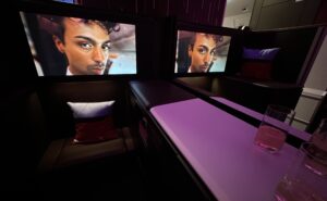 Large IFE screens show a mans face in the suite.