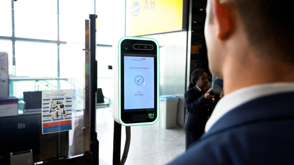 A passenger is standing in front of the biometric face scanner for British Airways.