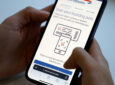 A passenger is holding a mobile device that says "scan your boarding pass"