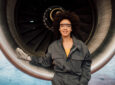 A smiling female engineer leaning on a commercial aircraft engine. mom guilt