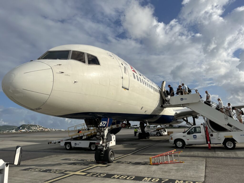 Passengers board the Delta 757 via air stairs.