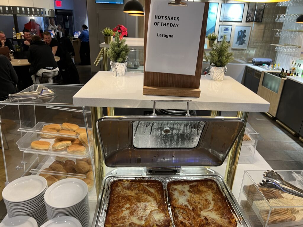 The lasagna in the SAS Newark lounge. Two pans of the pasta are flanked by rolls and dishes.