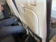 A man's knees are seen in close proximity to the Air France Recaro business class seatback.