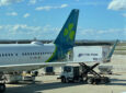 The tail of the Aer Lingus aircraft is seen from the airport window as it is parked at the gate. A shamrock on a blue tail.
