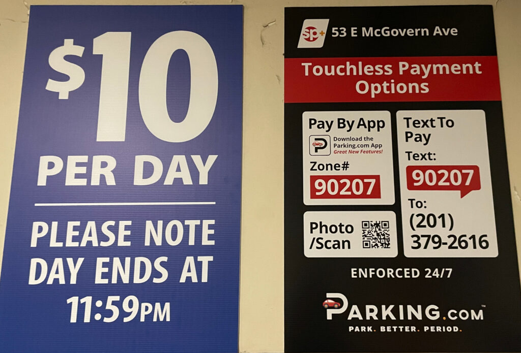 LNC's parking payment system. Two signs on the wall provide directions on how to pay via mobile app or text, and highlight that the parking costs $10 per day. 