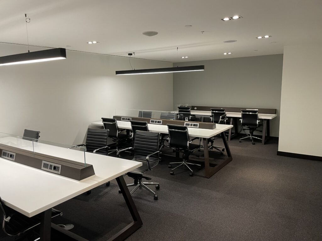 A room with three long tables and chairs with power stations in the center of the tables.