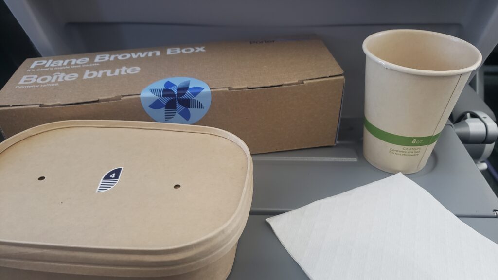 The various recyclable meal boxes and a recyclable cup displayed on the tray table.