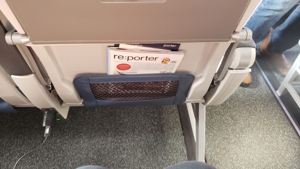 A PorterReserve seat is shown, with an emphasis on the legroom. The author's knees are barely visible in the photo, with plenty of distance between her and the seat in front.