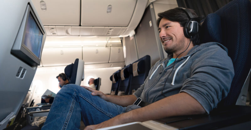 Man traveling by plane watching in-flight entertainment using earphones