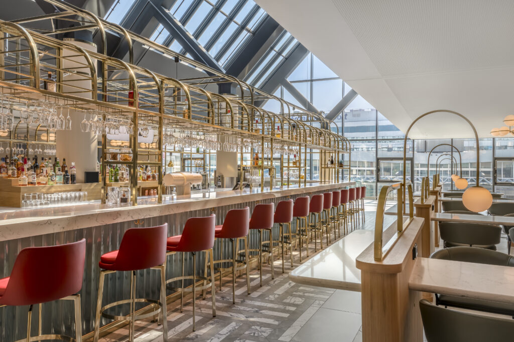 Big, bright and modern, The Eatery sparkles under the atrium. Red seats line the bar.