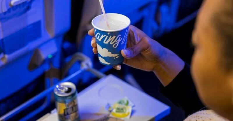 An Alaska Airlines passenger is holding the new paper cup