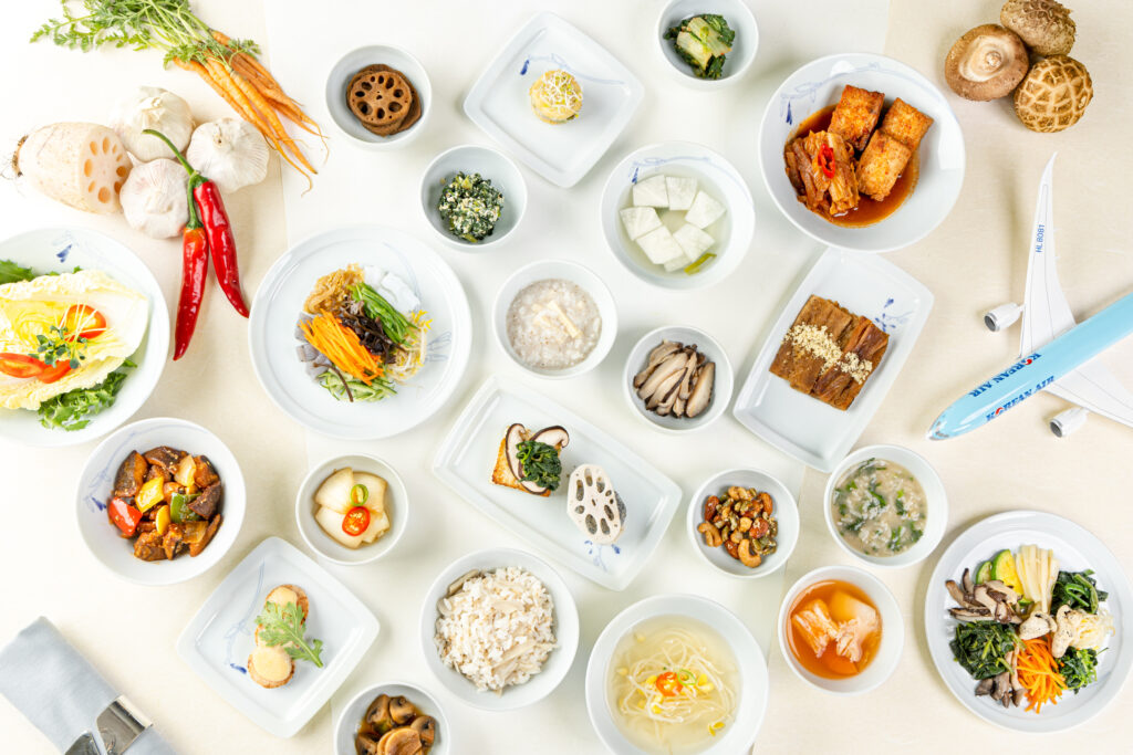 An assortment of Korean vegan dishes are displayed on white plates.