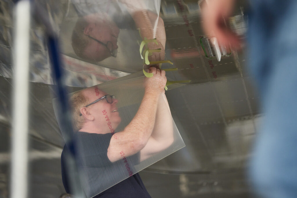 A man is applying the film to an aircraft.