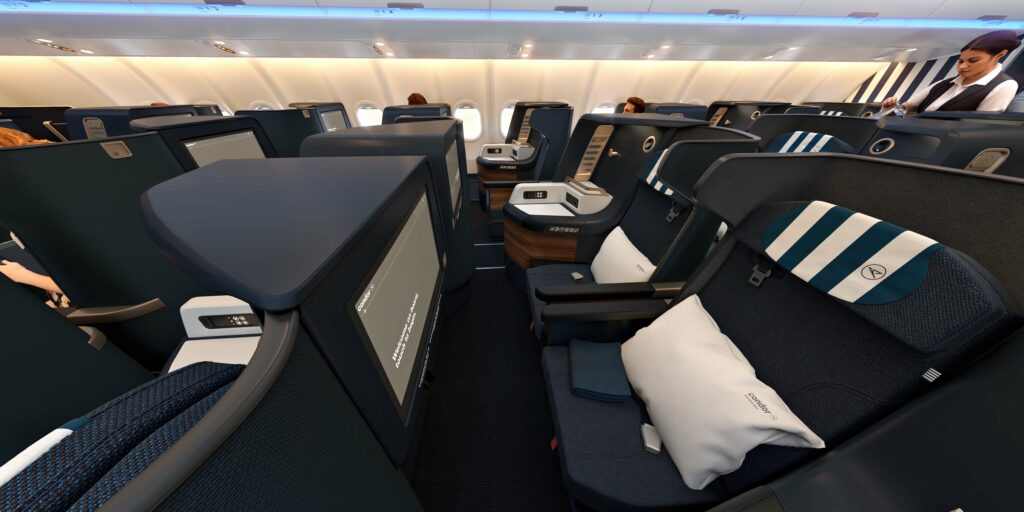 Deep dark blue covered business class seats with white stripes on the headrests and white pillows on the seat