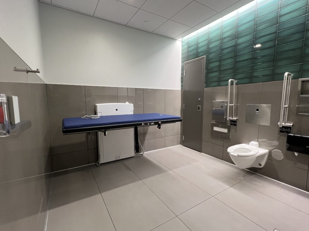 A spacious family restroom with a long changing table. 