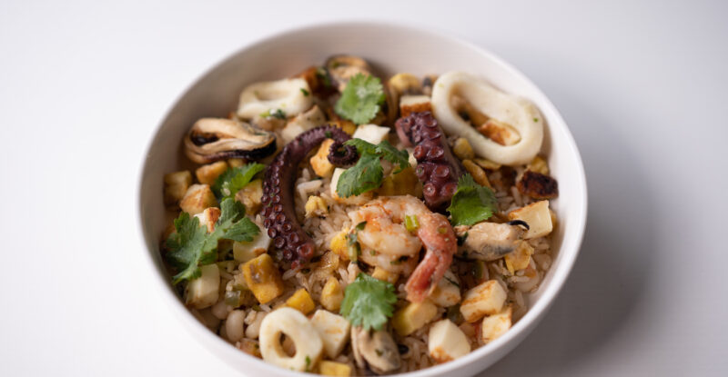 A seafood melody bowl with mixed veggies is sitting on a white table for LATAM's premium cabin catering.