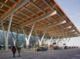 The exterior of Kansas City International Airport is floor to ceiling windows and a large overhang that is made of light coloured wood.