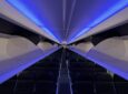 Alaska's Boeing 737-9 cabin interior. Blue LED lights are cascading over an empty cabin with open overhead bins.