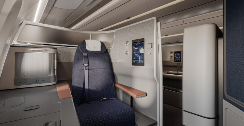 Lufthansa business class seat. The seat is rich blues with white thermoplastics and faux wood detailing. This is a window seat.