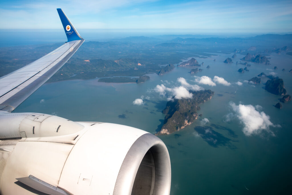 Image of Nok Air's aircraft engine and wing from the window of the aircraft. Islands and water can be seen below.