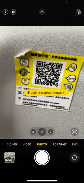 A QR code sticker is peeling off the surface of the Scoot tray table.