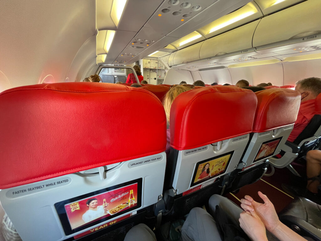 Aircraft interior of the Thai AirAsia A320. The seats in view feature red covers.